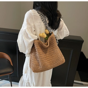 Détail du sac cabas en paille tissé avec bandoulière à rayures noires et blanches
