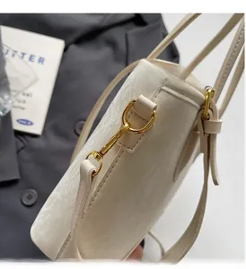 Gros plan sur la texture gaufrée blanc crème et les ferrures dorées du sac à main
