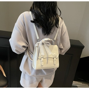 Rear view of model wearing white PU leather backpack with lace bows and silk scarf detail