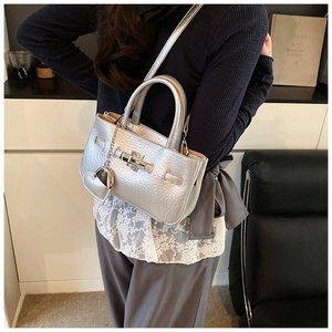 Detail view of silver litchi grain handbag with metal turn-lock and heart charm