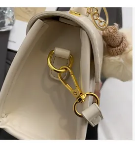Dettaglio di fibbia dorata e ciondolo di peluche su borsa bianca elegante