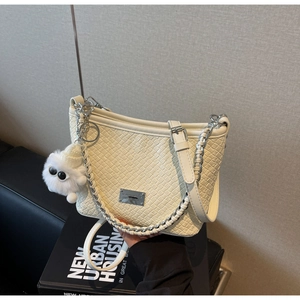 Detail of off-white woven shoulder bag featuring silver chain and fuzzy monster charm