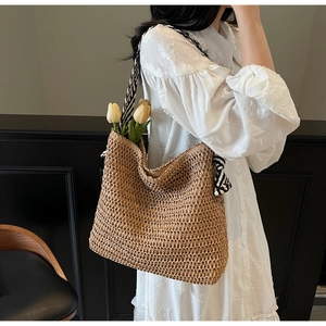 Détail d'un sac cabas en paille tissé avec une bandoulière rayée noire et blanche