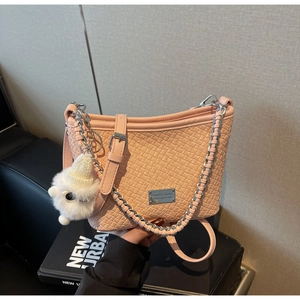 Close-up of peach woven texture bucket bag with silver chain and white plush charm