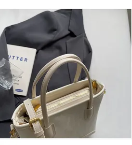 Détail du sac cabas en cuir crème avec fermeture éclair dorée et bandoulière réglable