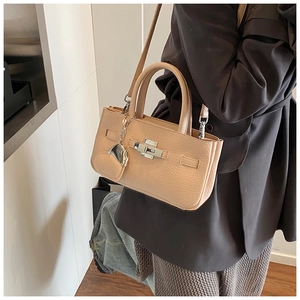 Detailed view of apricot bucket bag with silver turn-lock and heart pendant