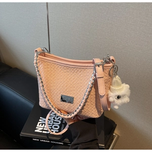 Detail of pink woven texture shoulder bag with silver chain and cute plush charm