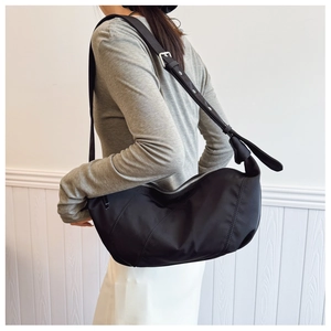 Detail of adjustable shoulder strap and silver buckle on black nylon hobo bag