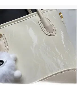 Détail du sac à main crème avec texture marbrée, boucles dorées et pendentif peluche