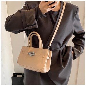 Detail of beige lychee leather crossbody bag with silver square twist lock on grey blazer