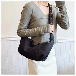 Detail of adjustable wide shoulder strap with metal buckles on black nylon hobo bag