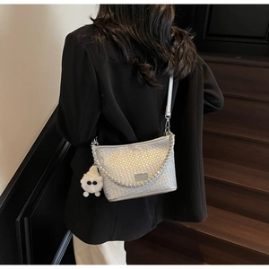Detail of silver woven hobo bag with metal chain and plush sheep charm on model