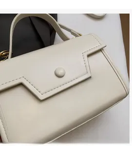 Dettaglio borsa crema con patta geometrica e fibbia rotonda di tendenza