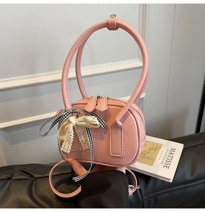 Dettaglio borsa rosa in pelle martellata con manico rotondo e decorazione a fiocco doppio
