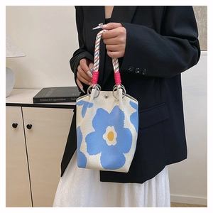 Detail van canvas emmer tas met grote blauwe bloemen en geweven touw handvaten