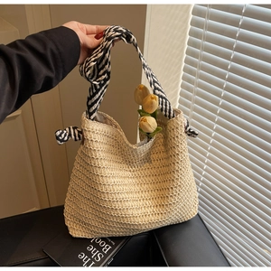 Gros plan du sac cabas en paille avec anses en tissu noué rayé noir et blanc élégant