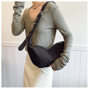Detail of black pleated crescent bag with adjustable wide strap and silver metal hardware