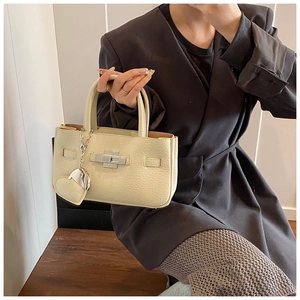 Detail of cream lychee texture leather handbag with silver lock and heart pendant