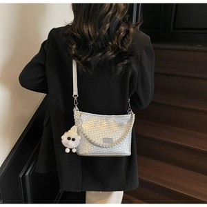 Close-up of silver woven shoulder bag with metal chain and cute plush sheep pendant