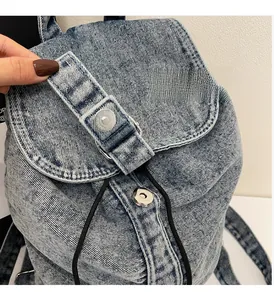 Détail d'un sac à dos en jean bleu clair avec boucle argentée et fermeture à cordon