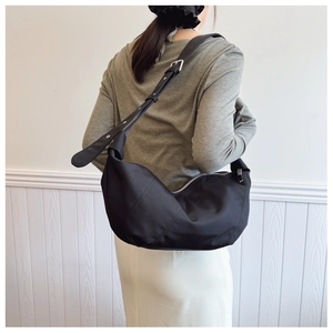 Detail of adjustable strap with silver buckle on black nylon crescent shoulder bag