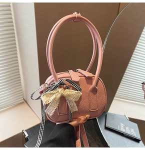Dettaglio della borsa rosa in pelle PU con texture litchi, fiocco in pizzo e nastro a quadri