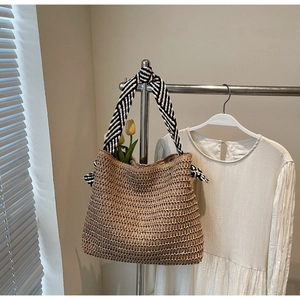 Détail d'un sac cabas en paille tissée avec anses rayées noires et blanches