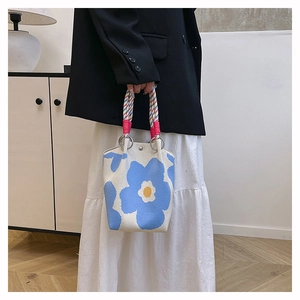 Detail van de grote blauwe gebreide bucket bag met kleurrijke gevlochten handvatten