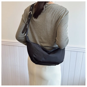 Detail of adjustable wide shoulder strap with silver buckle on black nylon hobo bag