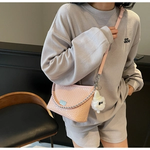 Detail of pink woven PU leather bag with silver metal tag and plush monster charm