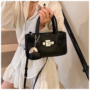 Detail of black leather crossbody bag featuring silver turn-lock and heart charm