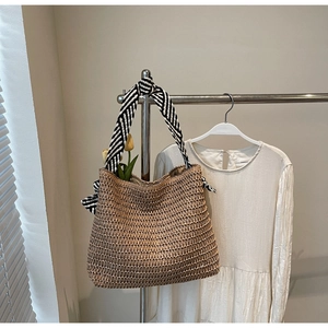 Détail d'un sac cabas en paille tissé avec des poignées rayées noires et blanches déco