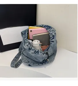 Intérieur spacieux du sac à dos en denim bleu montrant ordinateur et accessoires