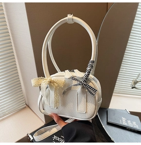 Dettaglio della mini borsa a cilindro bianca con trama litchi, fiocchi e manici tondi