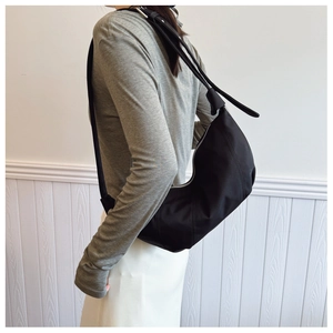 Detail showing the black pleated nylon dumpling bag with silver zipper on model