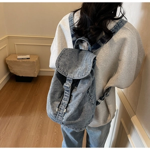 Détail d'un sac à dos en denim délavé avec boucles métalliques et texture vintage