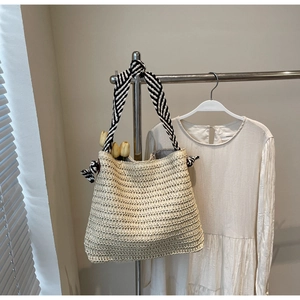 Détail du sac en paille avec bandoulière nouée à rayures noires et blanches et tulipe
