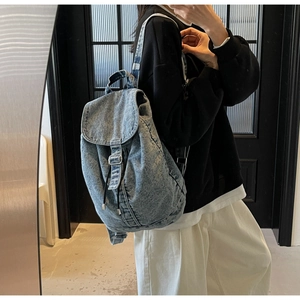 Détail d'un sac à dos vintage en denim délavé avec boucle argentée et cordon de serrage