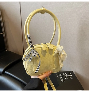 Dettaglio della borsa gialla con grana litchi e decorazione di nastri e pizzi