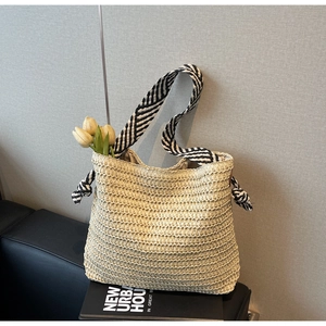 Texture détaillée du sac cabas en paille avec bandoulière à rayures noires et blanches