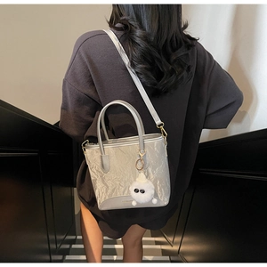 Détail du mini sac seau gris argent avec breloque peluche porté au dos du mannequin