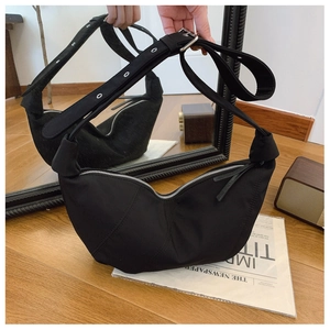 Detail view of black nylon crescent bag with silver eyelet strap and zipper closure