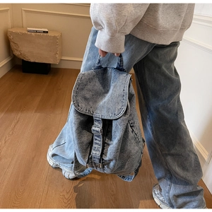 Détail du sac à dos en denim bleu vintage avec boucle métallique et poignée de transport