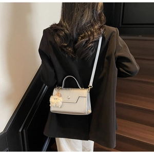 Piccola borsa quadrata argento lucido con ciondolo di peluche vista sulla modella