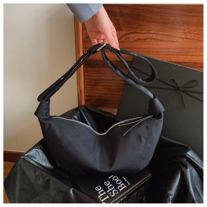 Detail of black pleated hobo bag with silver zipper and adjustable wide shoulder strap