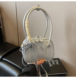 Dettaglio mini borsa argento in pelle martellata con manici ad anello e fiocco pizzo