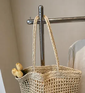 Primer plano del bolso de paja tejida color crema con asas trenzadas fuertes