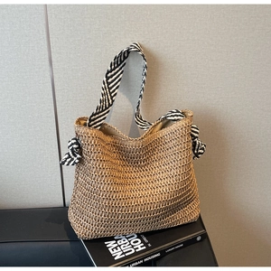 Détail du sac cabas en paille avec bandoulières rayées noir et blanc sur bureau épuré