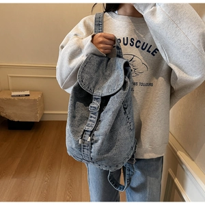 Sac à dos en denim délavé bleu avec rabat supérieur, boucle en métal argenté et cordon de serrage