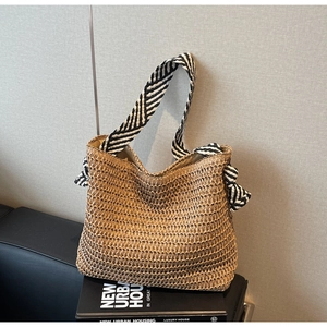 Détail du sac cabas en paille tissé avec sangle rayée et nœud décoratif élégant